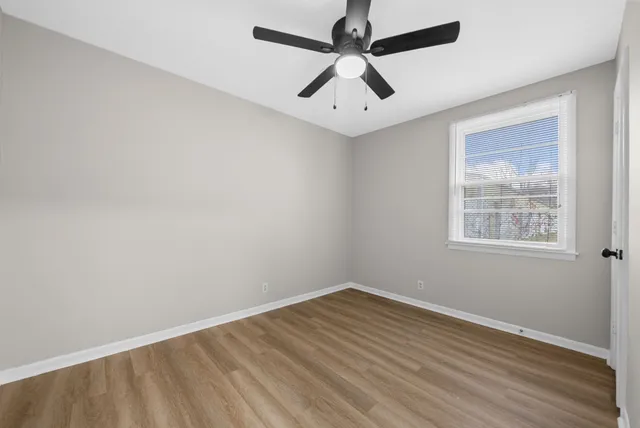 an empty room with a window and a fan