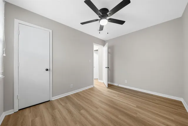 an empty room with wooden floor and ceiling fan