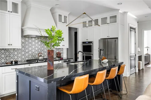 a kitchen with stainless steel appliances granite countertop a table and chairs in it