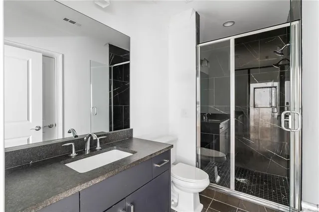 a bathroom with a granite countertop sink toilet and shower