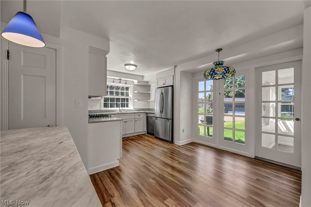 3543 Lytle Road Shaker Heights, OH 44122 - Photo 15 of 49 Open-concept kitchen and dining area featuring wood-finish flooring, white cabinetry, a stainless steel refrigerator, and glass-paned French doors opening to an outdoor space