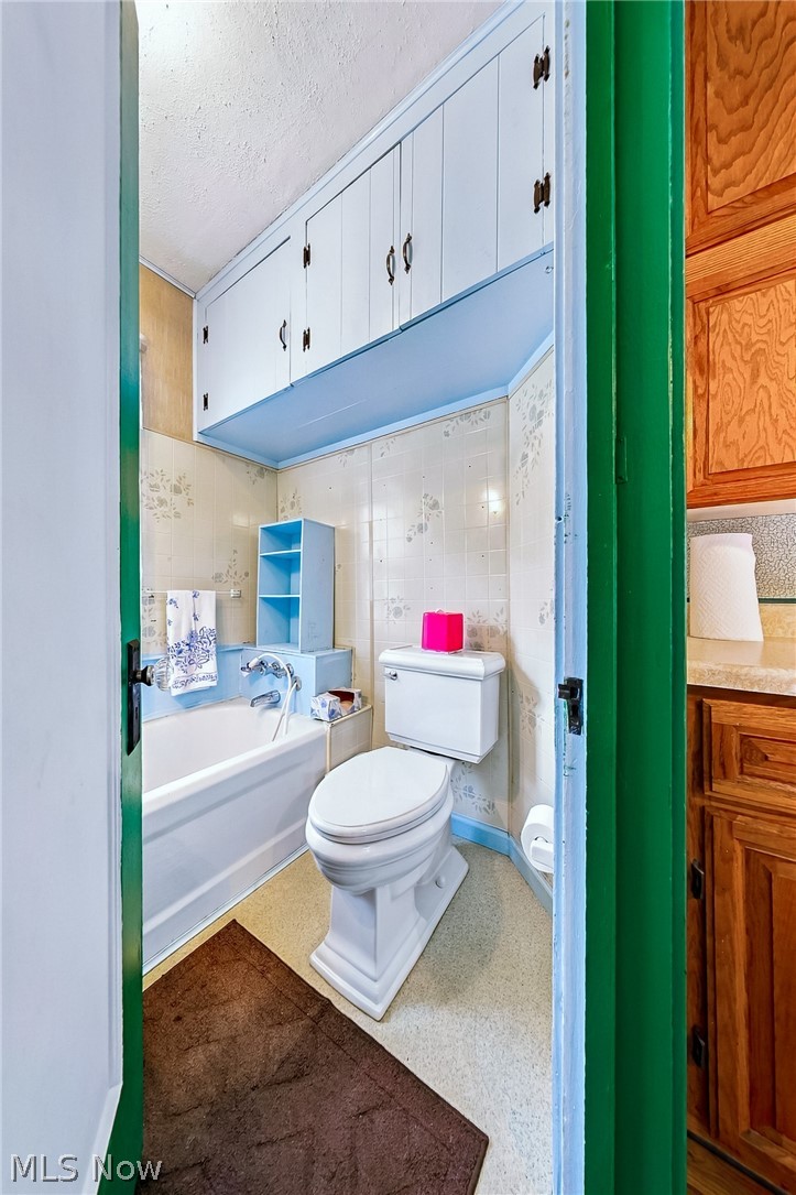 24958 Kennedy Ridge Road North Olmsted, OH 44070 - Photo 17 of 43 Built-in overhead cabinetry, white toilet, white bathtub, blue wall shelving, light-colored flooring