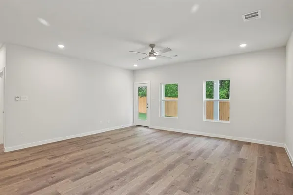 an empty room with wooden floor and windows
