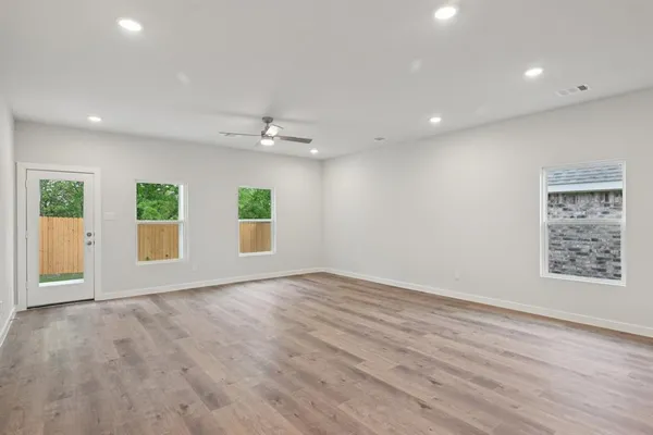 an empty room with wooden floor and windows