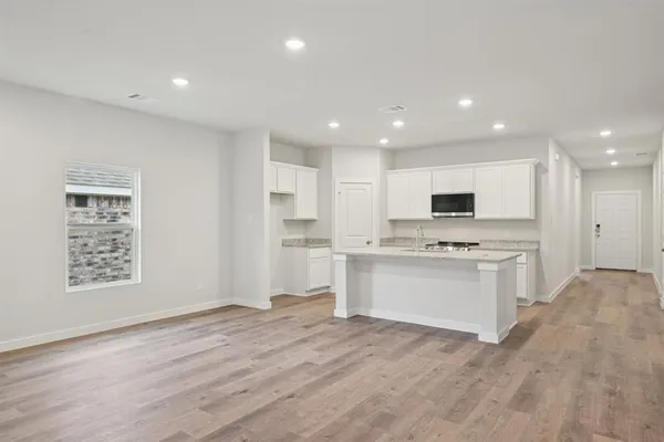 a large white kitchen with kitchen island a sink white cabinets and white appliances
