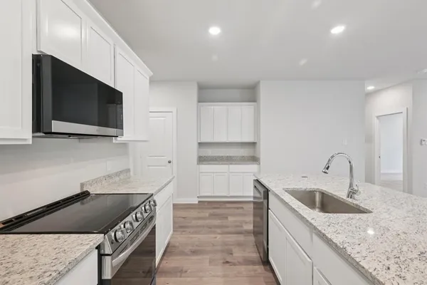 a kitchen with a sink and a stove top oven with wooden floor