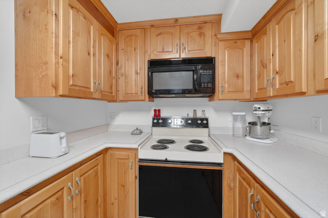883 East 700 South Springville, UT 84663 - Photo 35 of 59 U-shaped kitchen featuring light wood cabinetry with arched top panels, a built-in black microwave, and white countertops