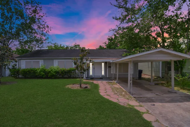 a front view of a house with a garden and trees