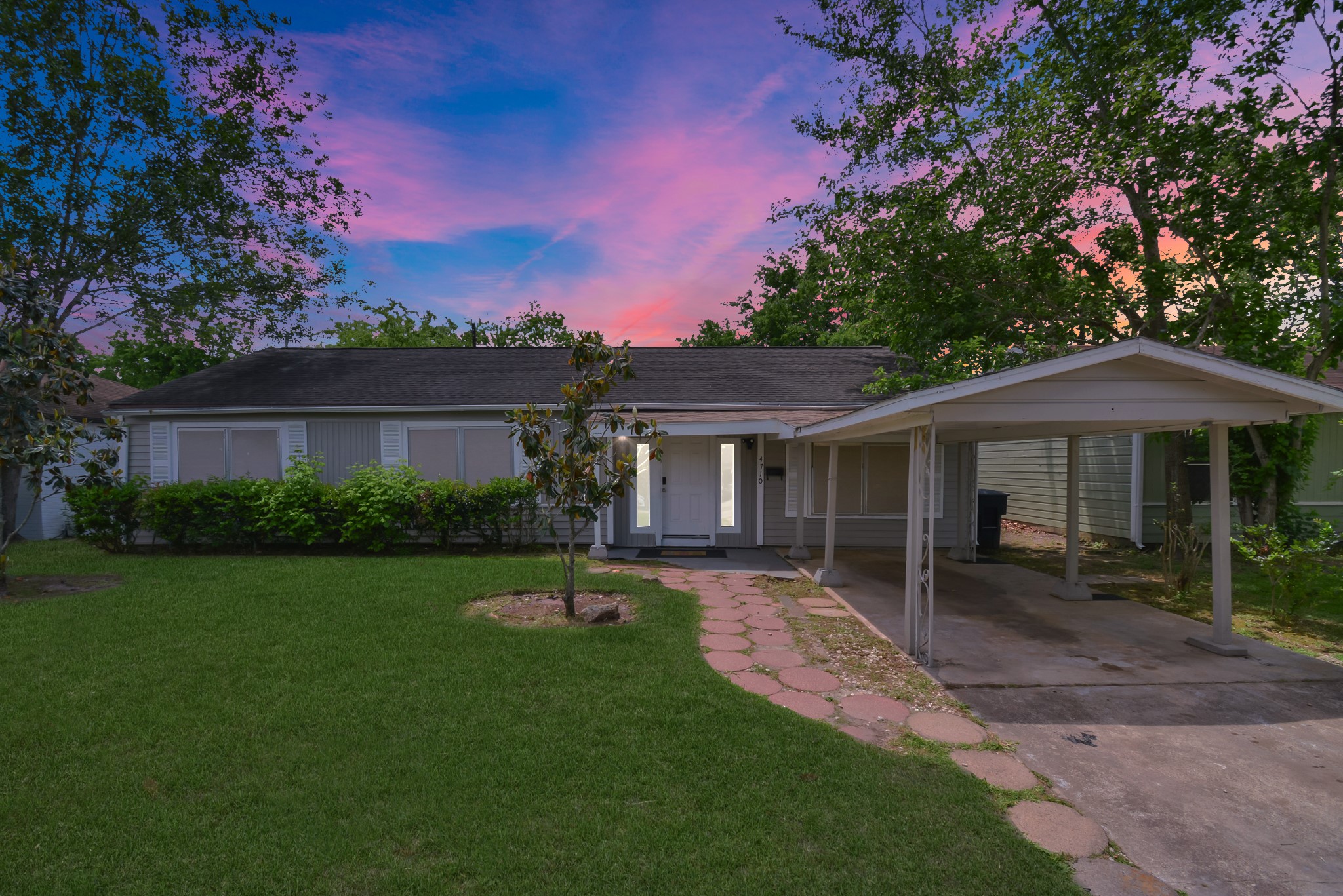 a front view of a house with a garden and trees