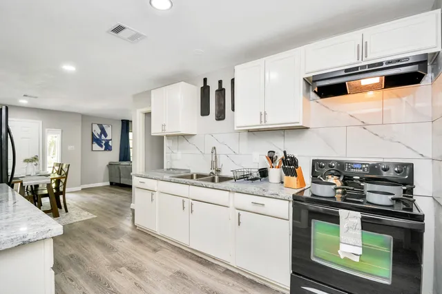 a kitchen with stainless steel appliances granite countertop a stove and white cabinets