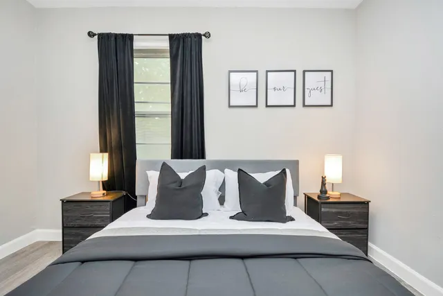 a large white bed sitting in a living room next to a window