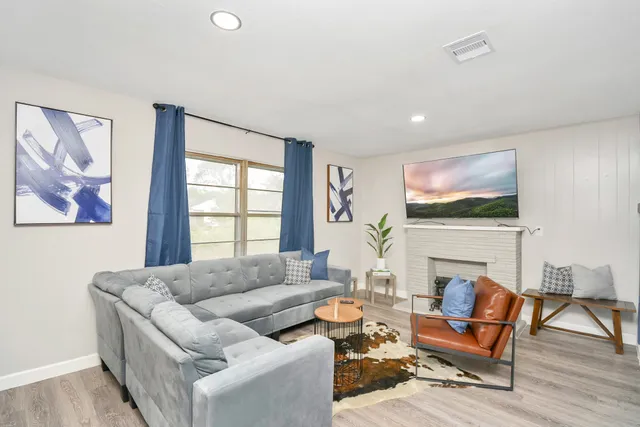 a living room with furniture a flat screen tv and a large window
