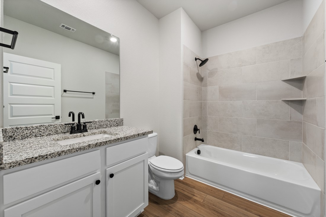 9316 Gladsome Path Manor, TX 78653 - Photo 12 of 18 a bathroom with a granite countertop toilet a sink and a bathtub