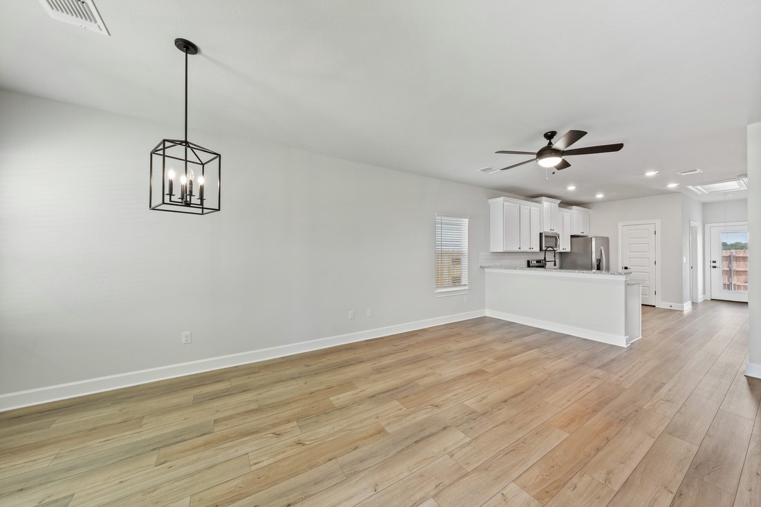 9316 Gladsome Path Manor, TX 78653 - Photo 4 of 18 a view of a kitchen with wooden floor and a ceiling fan