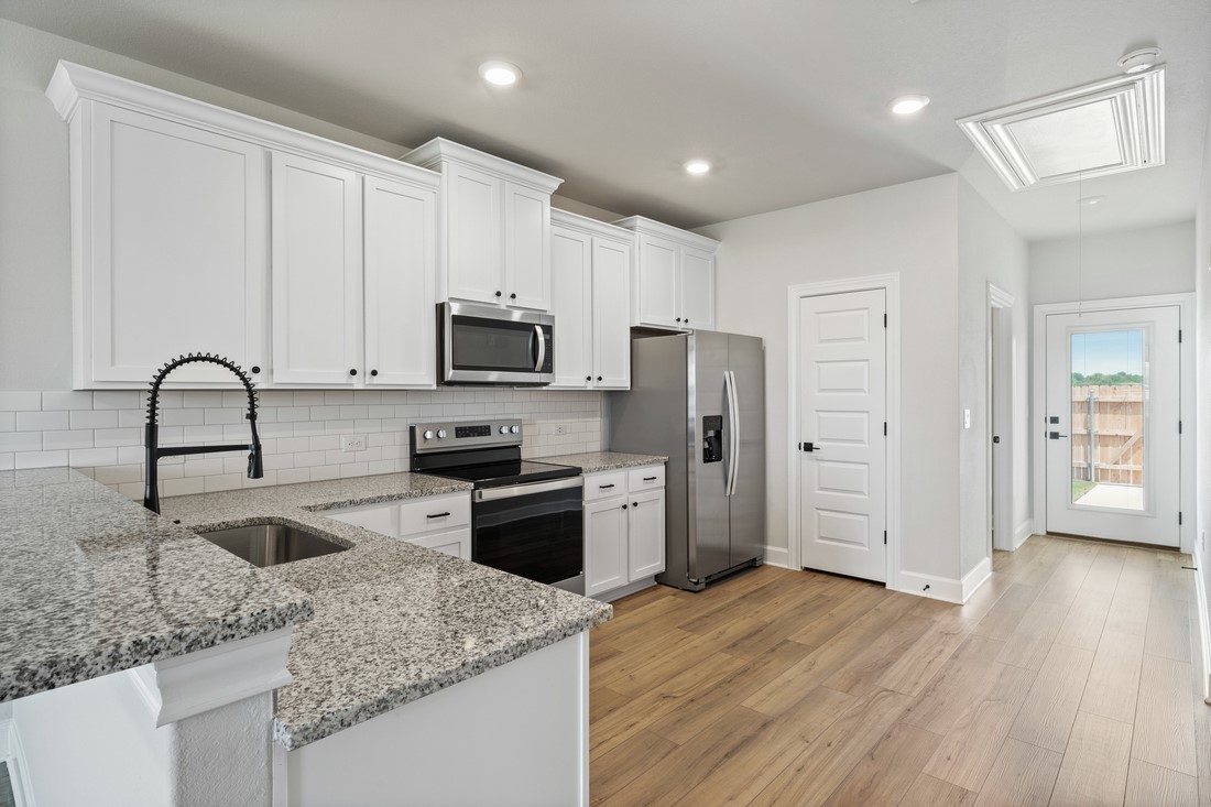 9316 Gladsome Path Manor, TX 78653 - Photo 6 of 18 a kitchen with granite countertop a refrigerator stove and sink