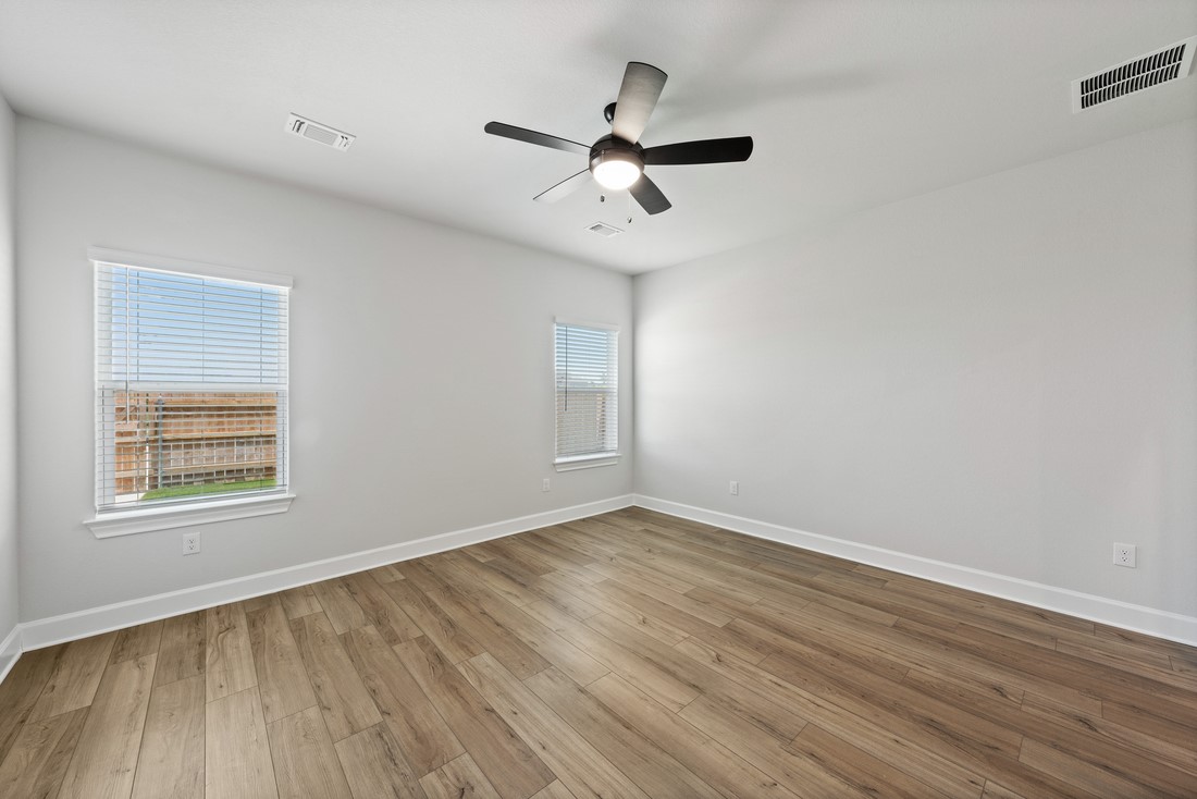 9316 Gladsome Path Manor, TX 78653 - Photo 9 of 18 an empty room with wooden floor ceiling fan and windows