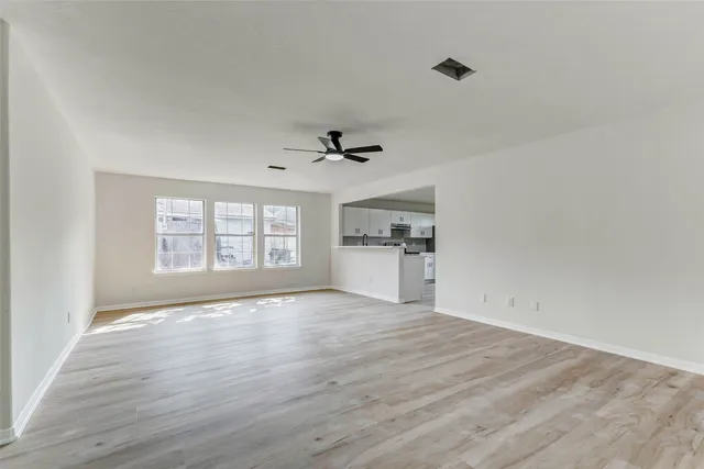 a view of an empty room with a window and wooden floor