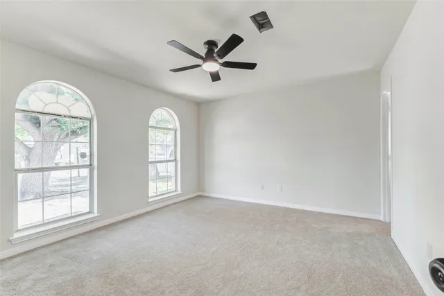 an empty room with windows and ceiling fan