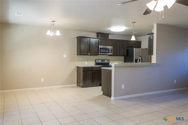 a view of an empty room with window and chandelier fan