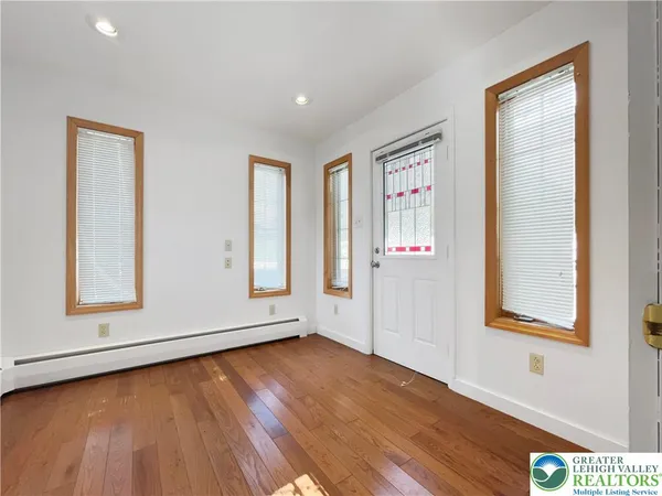an empty room with wooden floor and windows