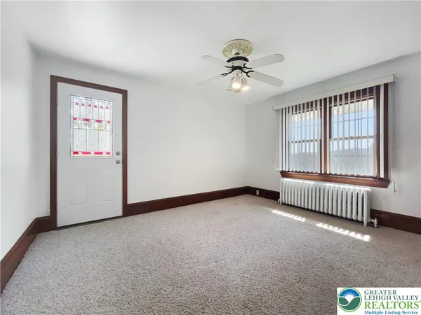an empty room with windows and ceiling fan