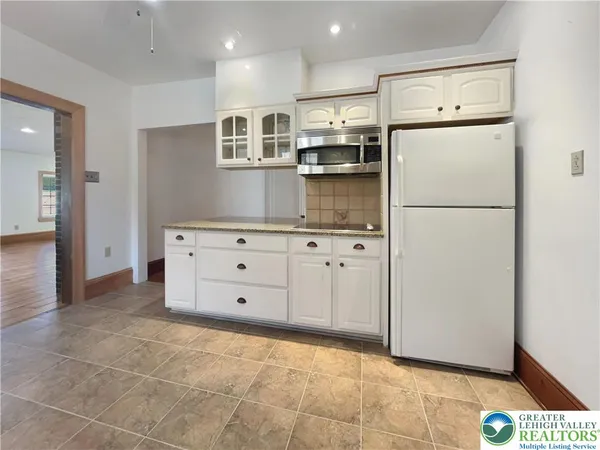 a kitchen with kitchen island white cabinets and refrigerator