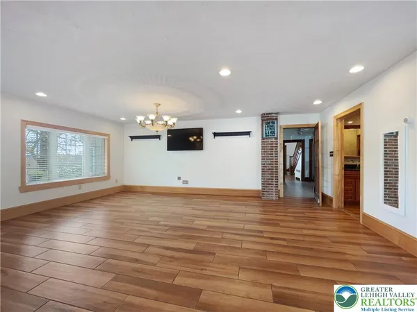 a view of an empty room with window and wooden floor