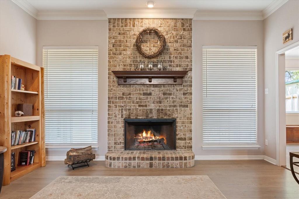 111 Spring Creek Street Waco, TX 76705 - Photo 11 of 40 Brick fireplace with a wood mantel, crown molding, and wood-finish flooring