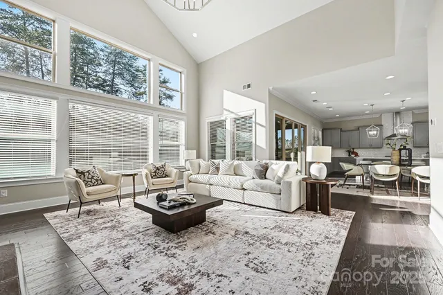 a living room with furniture large windows and wooden floor