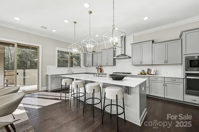 a kitchen with stainless steel appliances granite countertop a stove a sink dishwasher a refrigerator with white cabinets and wooden floor