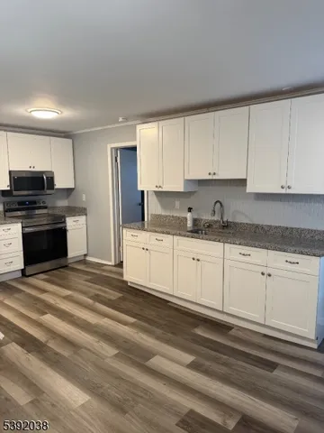 a kitchen with granite countertop white cabinets and stainless steel appliances