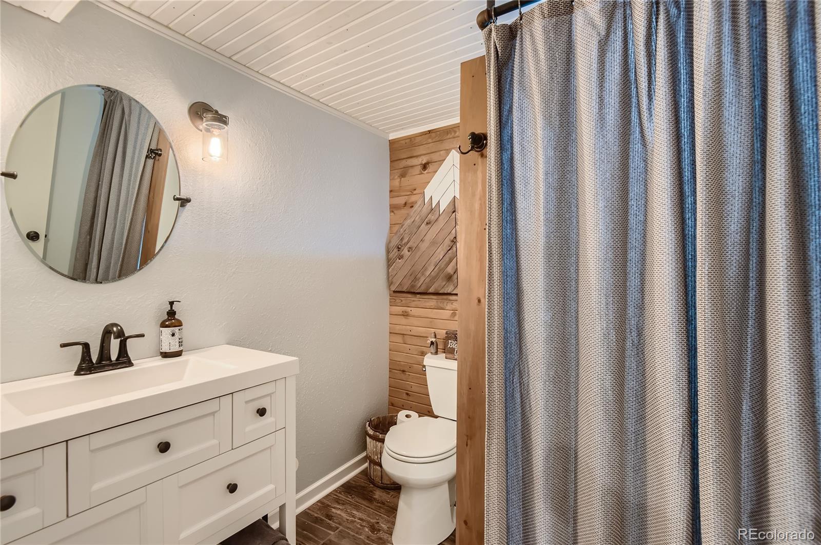 9212 Princeton Street Highlands Ranch, CO 80130 - Photo 34 of 40 a bathroom with a toilet a sink and a mirror
