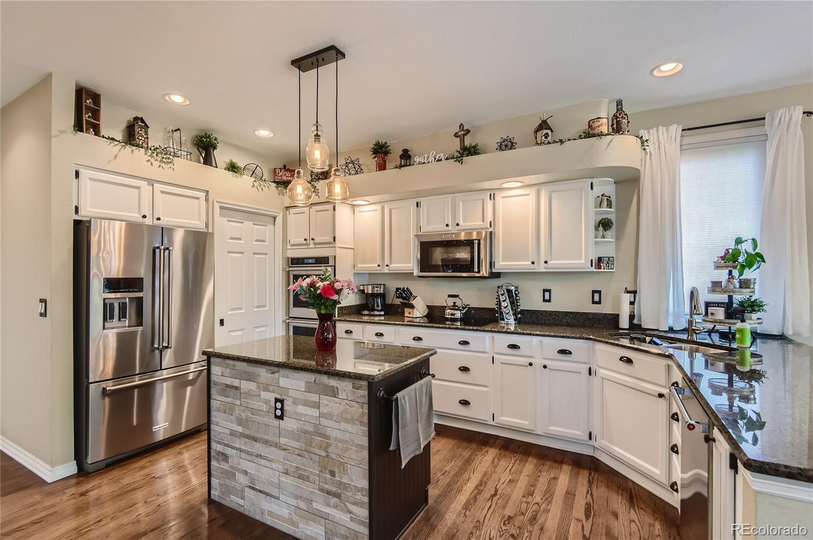 9212 Princeton Street Highlands Ranch, CO 80130 - Photo 9 of 40 a kitchen with white cabinets and stainless steel appliances