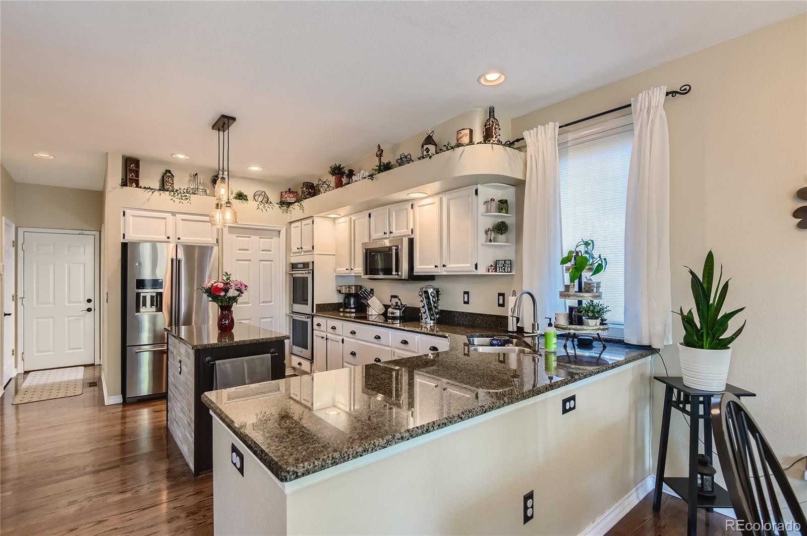 9212 Princeton Street Highlands Ranch, CO 80130 - Photo 10 of 40 a kitchen with stainless steel appliances granite countertop a sink a stove and a wooden floor