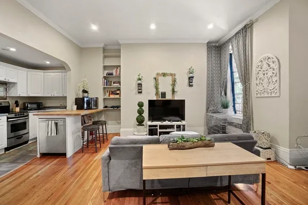 a large kitchen with a table chairs a sink dishwasher stove and cabinets with wooden floor