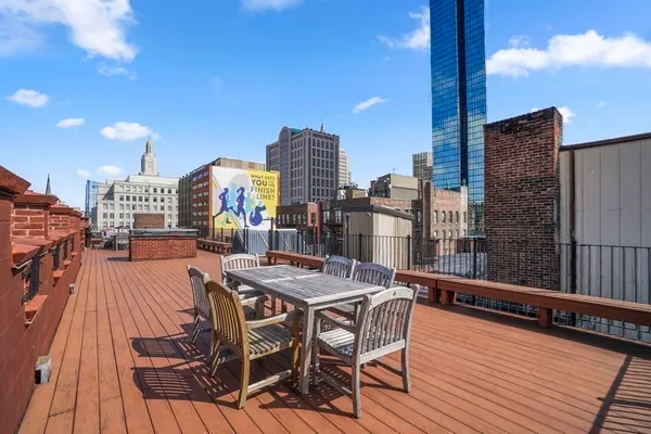 a view of a rooftop deck with chairs and wooden floor