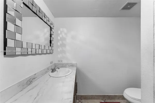 a bathroom with a granite countertop bathtub sink vanity mirror and toilet