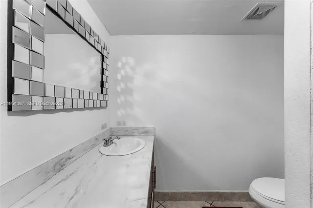 a bathroom with a granite countertop bathtub sink vanity mirror and toilet