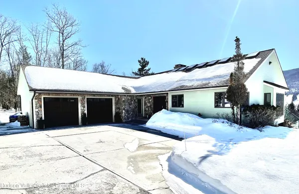 a front view of a house with a yard covered with snow and trees