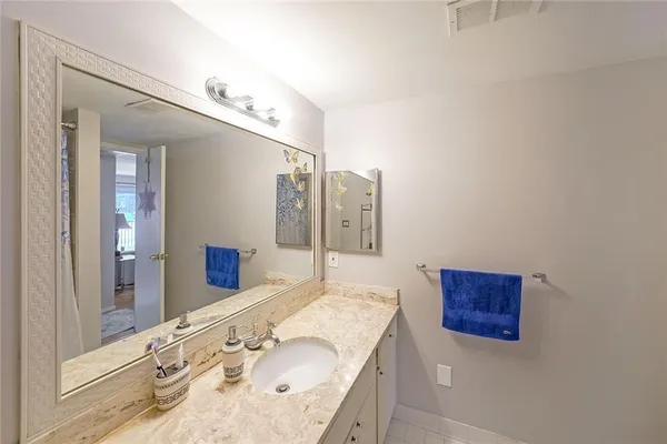 a bathroom with a granite countertop double vanity sink and mirror