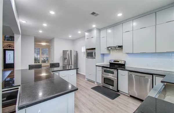 a large kitchen with stainless steel appliances granite countertop a sink a stove and a wooden floors