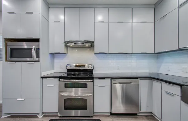 a kitchen with granite countertop cabinets stainless steel appliances and wooden floor