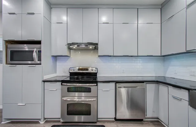 a kitchen with granite countertop cabinets stainless steel appliances and wooden floor