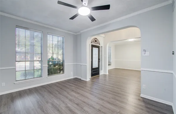 a view of empty room with wooden floor and fan