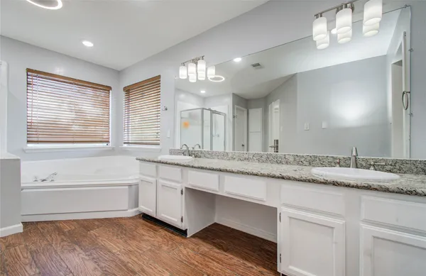 a bathroom with double vanity sinks a vanity a lamp and a window