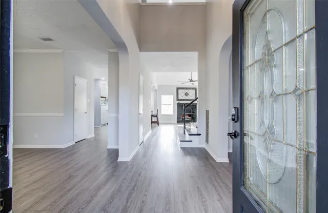 a view of a hallway with wooden floor and a bathroom