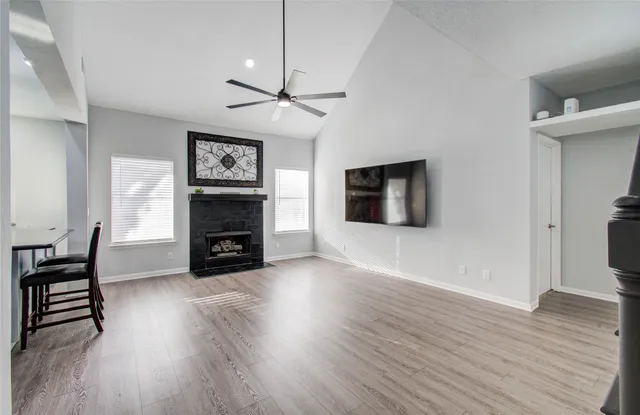 an empty room with wooden floor fireplace and windows