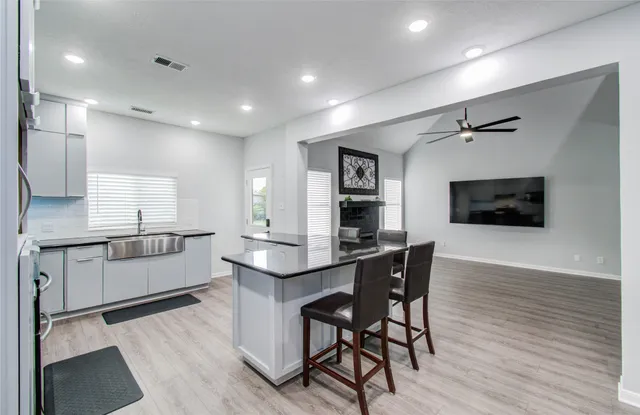 a kitchen with stainless steel appliances kitchen island granite countertop a wooden table chairs and granite counter tops