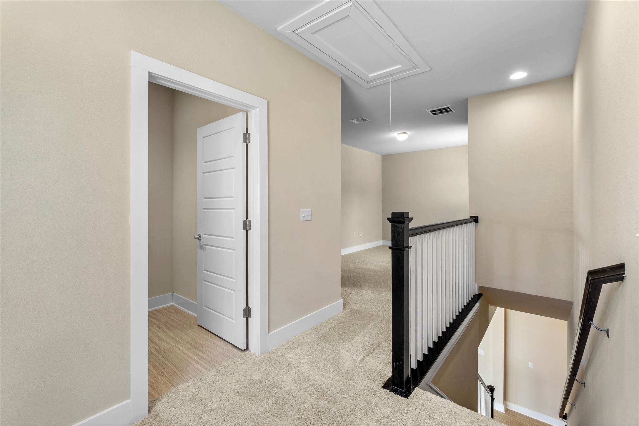 1709 Lawrence Street, Unit 5 Austin, TX 78741 - Photo 20 of 40 An upper landing features plush carpeting and a wooden staircase railing overlooking the lower level.