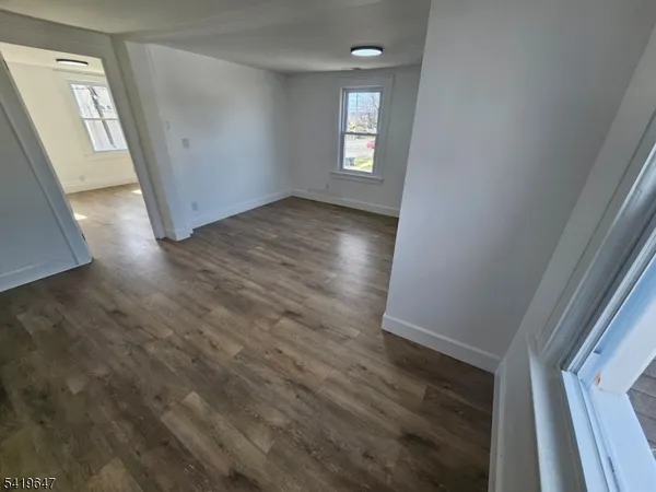a view of empty room with window and wooden floor